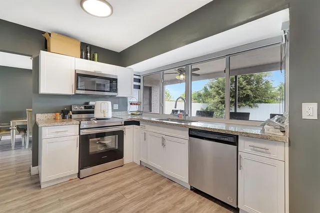 a kitchen with stainless steel appliances granite countertop a sink and wooden cabinets