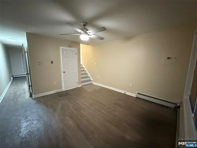 an empty room with wooden floor closet and fan