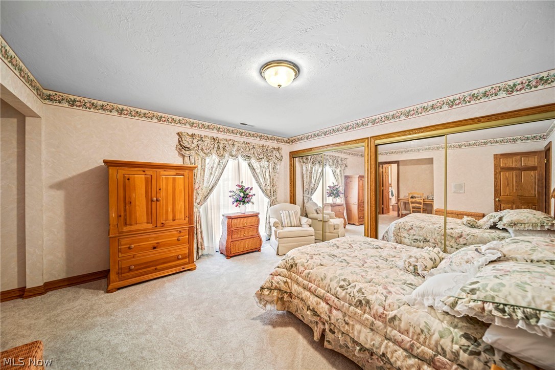 8801 Bunker Road Orwell, OH 44076 - Photo 37 of 50 Bedroom with light carpet, two closets, a textured ceiling, and wallpapered walls