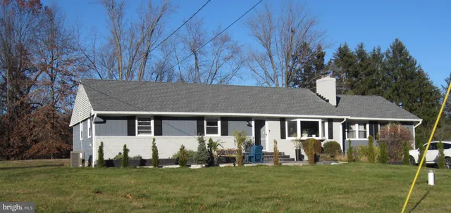 a view of a white house with a big yard and potted plants and trees