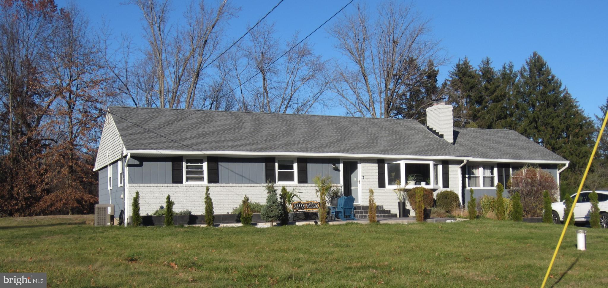 a view of a white house with a big yard and potted plants and trees