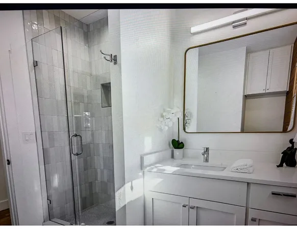 a bathroom with a granite countertop sink a mirror and shower