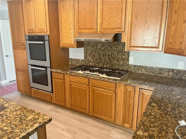 a kitchen with stainless steel appliances granite countertop a stove a sink and a microwave