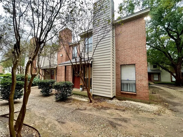 a backyard of a house with potted plants and a large tree