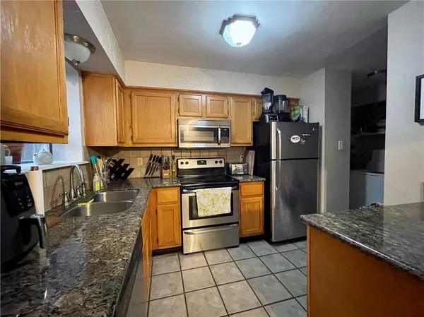 a kitchen with granite countertop a refrigerator a stove and a sink