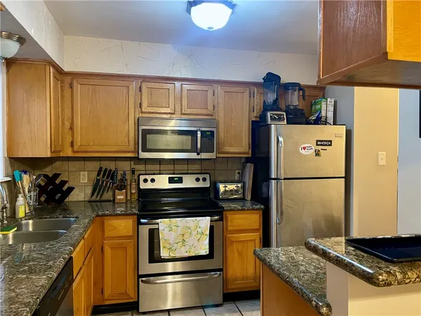 a kitchen with stainless steel appliances granite countertop a refrigerator a stove and a sink with wooden floor