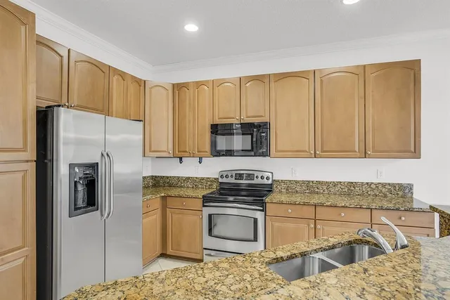 a kitchen with granite countertop a sink stove and refrigerator