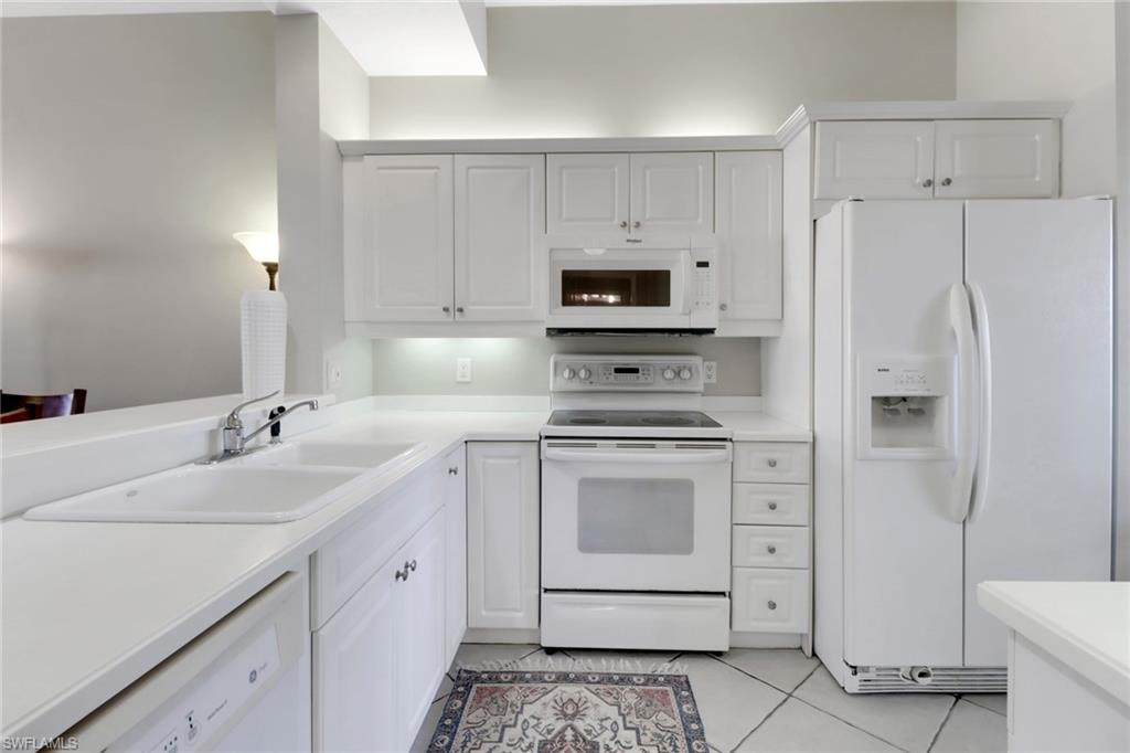401 Bayfront Place, Unit 3502 Naples, FL 34102 - Photo 4 of 22 Kitchen with white appliances, light tile patterned flooring, light countertops, and white cabinets