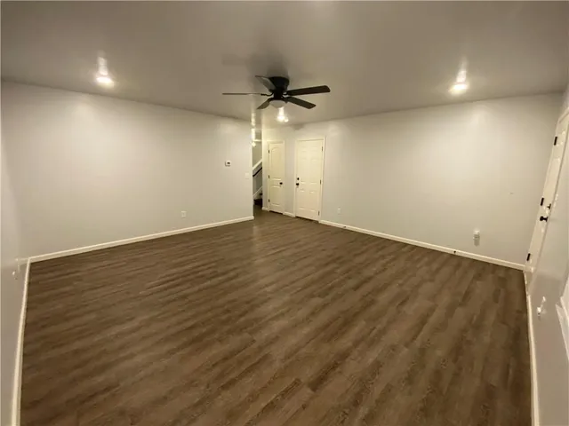 an empty room with a ceiling fan and wooden floor