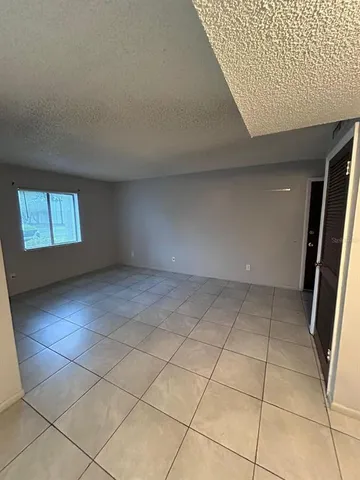 a view of a refrigerator in kitchen and an empty room