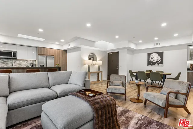 a kitchen with stainless steel appliances granite countertop a refrigerator a stove a sink a dining table and chairs with wooden floor