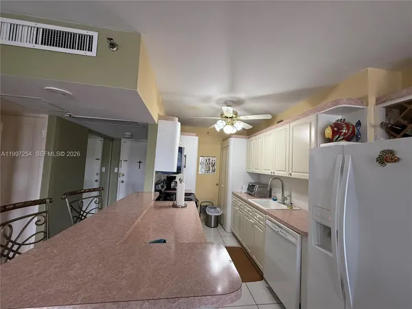a large white kitchen with cabinets a sink and appliances