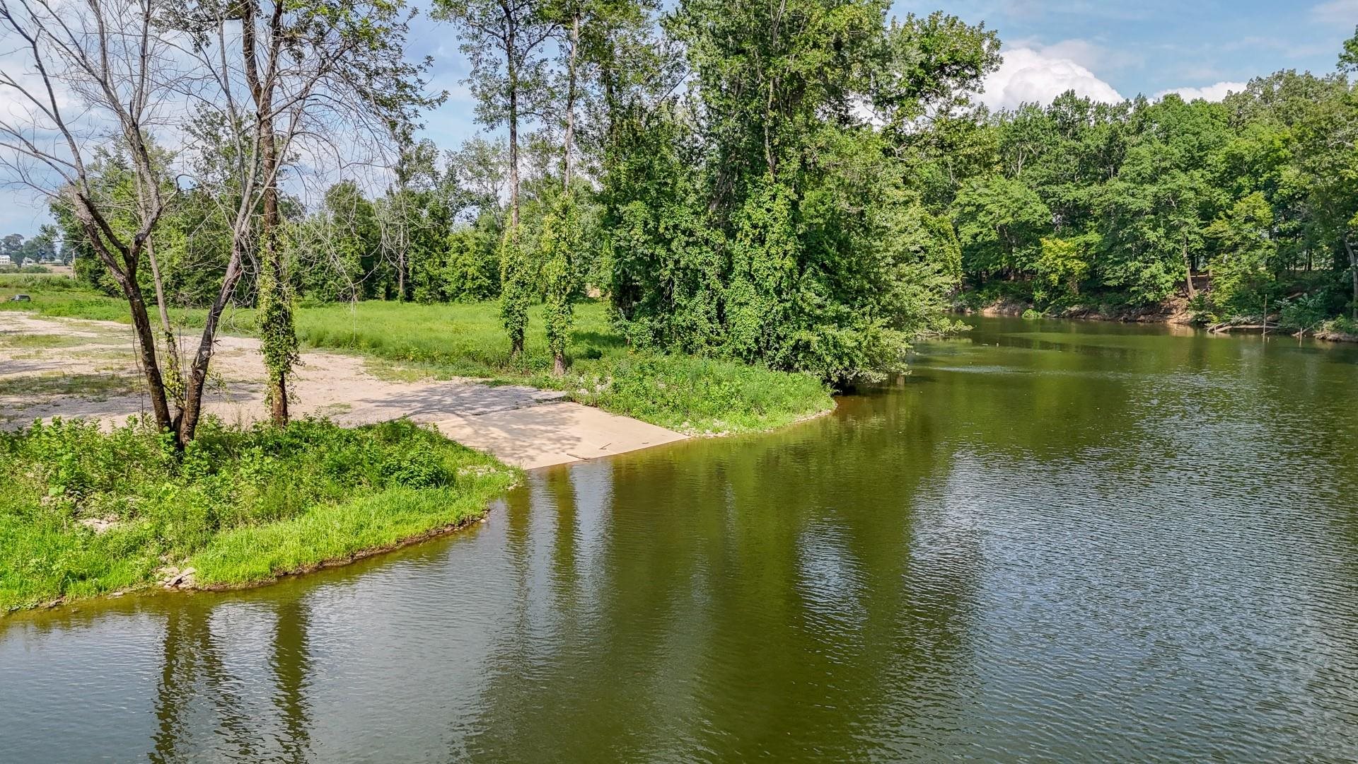 a view of a lake with a yard and large trees