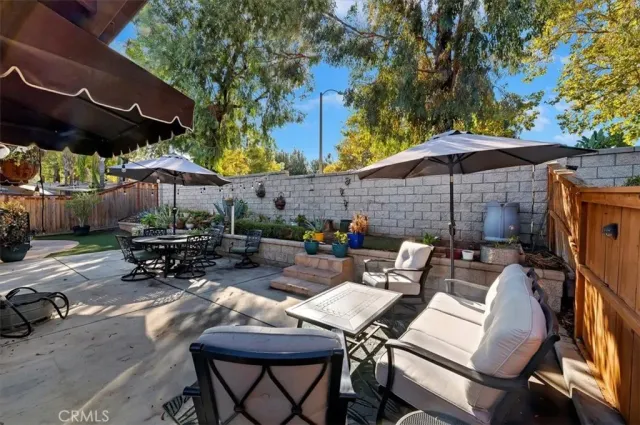 a view of a patio with table and chairs under an umbrella with a barbeque