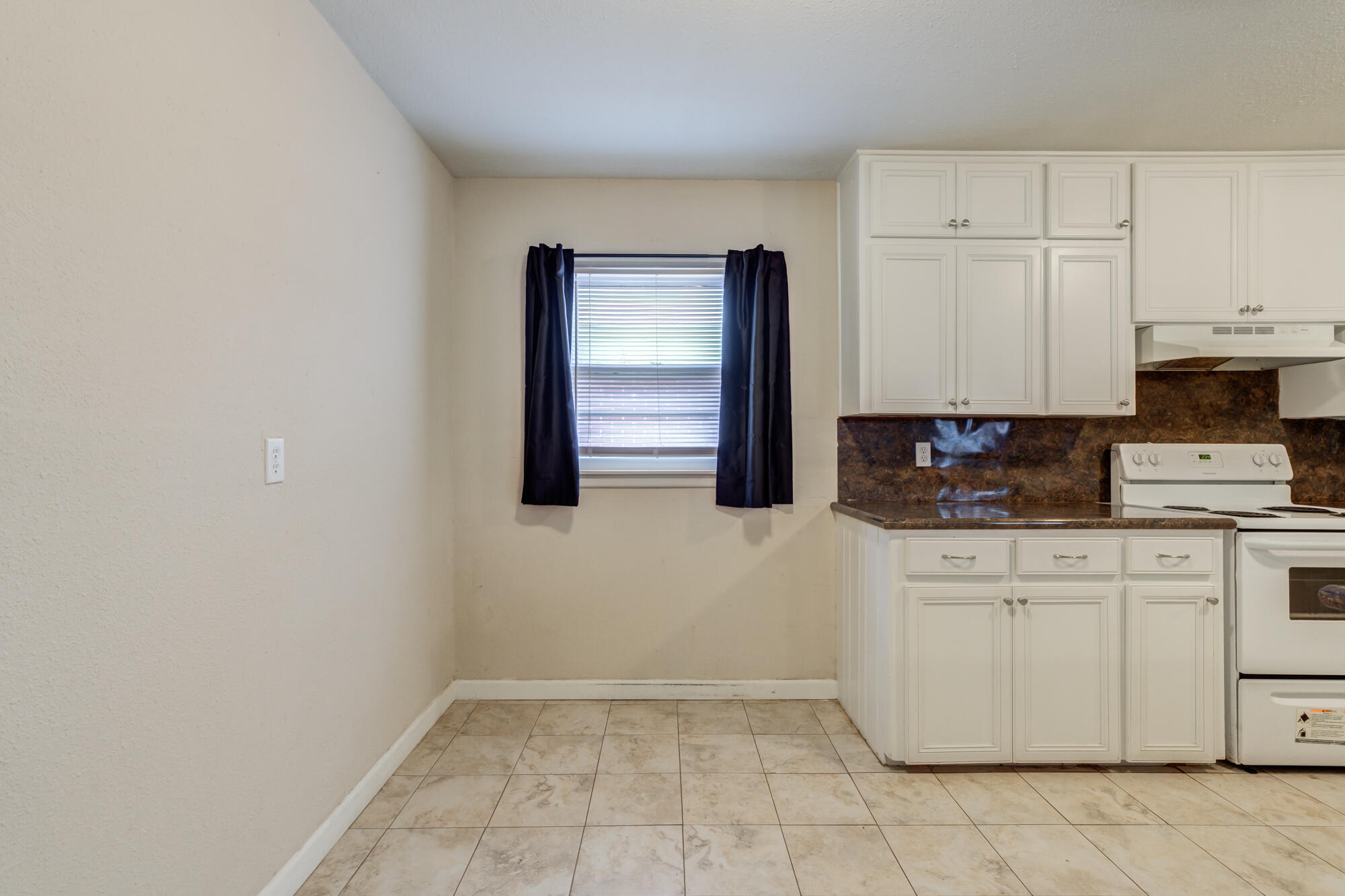 403 East 19th Street Littlefield, TX 79339 - Photo 19 of 34 a kitchen with granite countertop white cabinets and stainless steel appliances