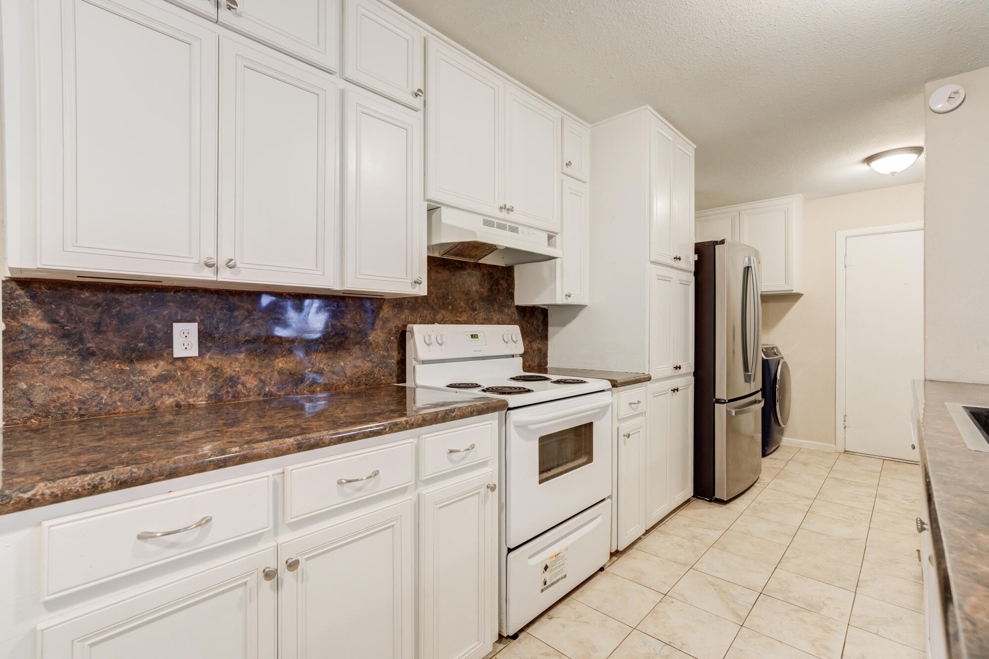 403 East 19th Street Littlefield, TX 79339 - Photo 20 of 34 a kitchen with granite countertop white cabinets and stainless steel appliances