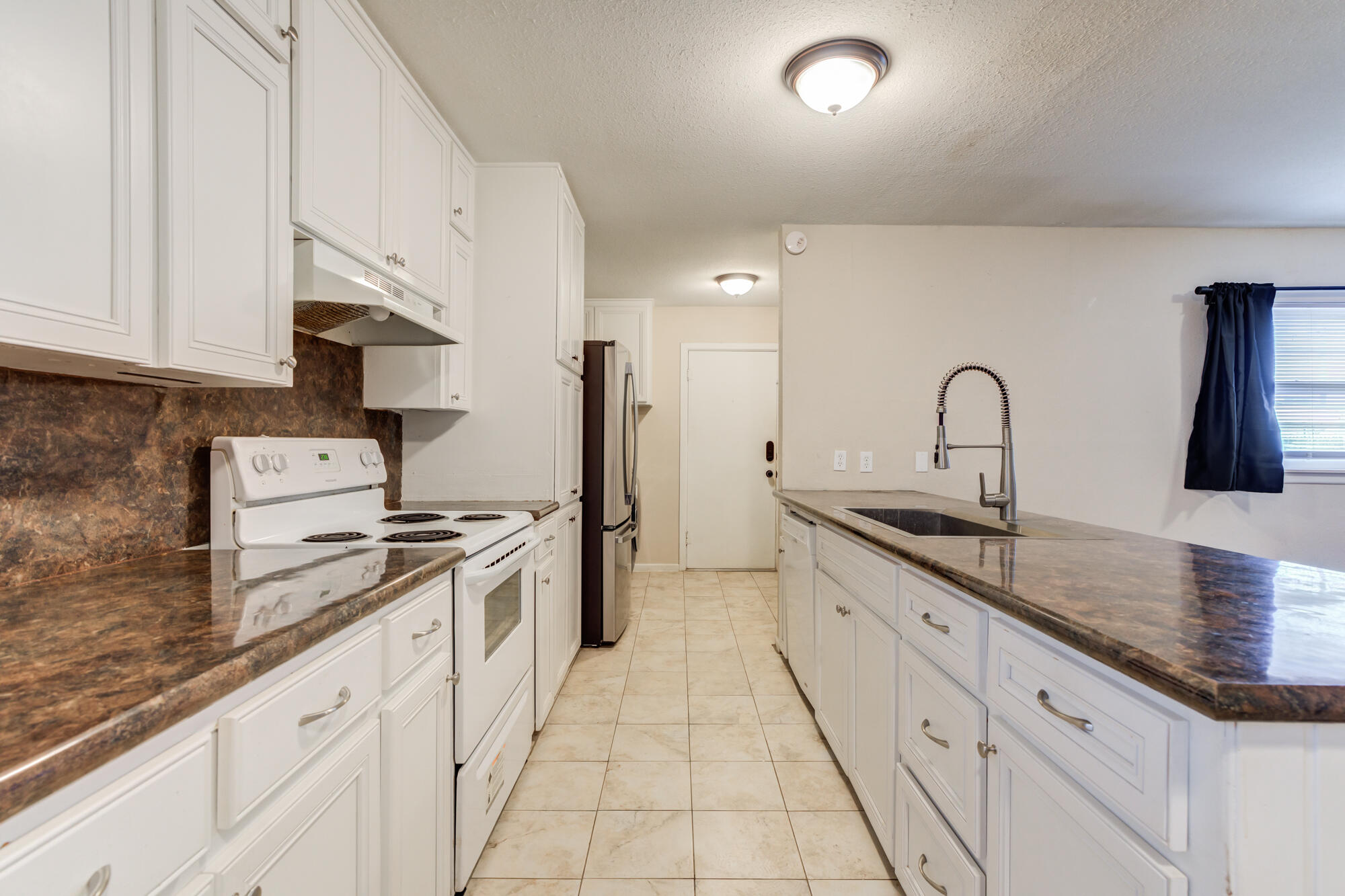 403 East 19th Street Littlefield, TX 79339 - Photo 21 of 34 a kitchen with granite countertop a sink stove and cabinets