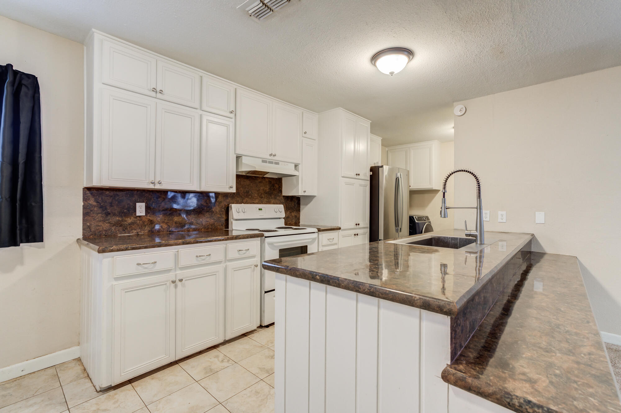 403 East 19th Street Littlefield, TX 79339 - Photo 3 of 34 a kitchen with stainless steel appliances granite countertop a sink a stove and white cabinets