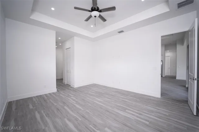 an empty room with wooden floor ceiling fan and windows