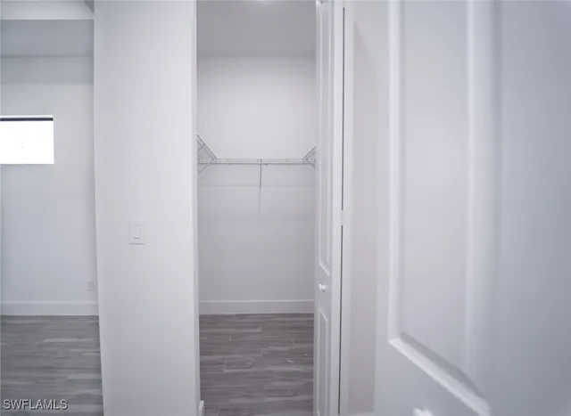 a view of an empty room with wooden floor and a ceiling fan
