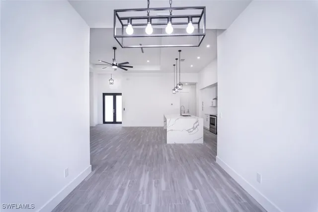 a large white kitchen with a stove a sink dishwasher a refrigerator and a fireplace with wooden floor