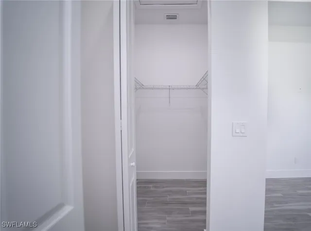 an empty room with wooden floor chandelier fan and windows