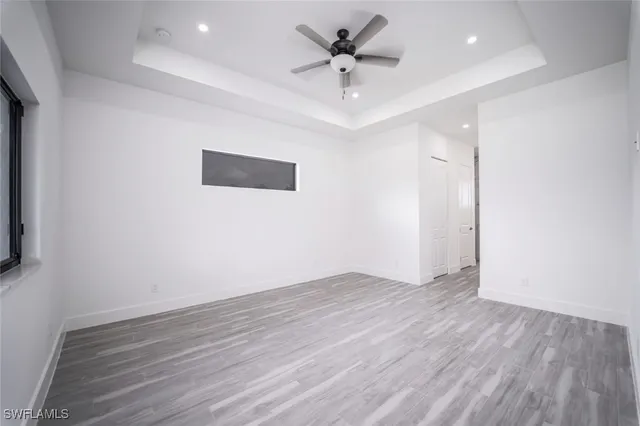 an empty room with wooden floor and a ceiling fan