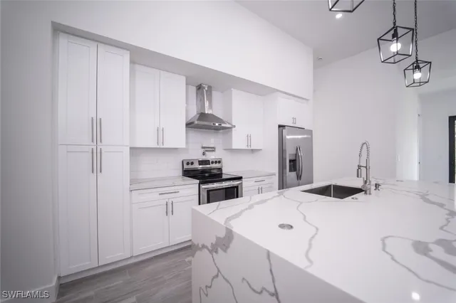 a kitchen with stainless steel appliances a sink a stove a refrigerator cabinets and a dining table