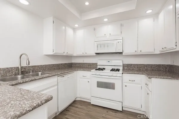 a kitchen with granite countertop white cabinets and white appliances