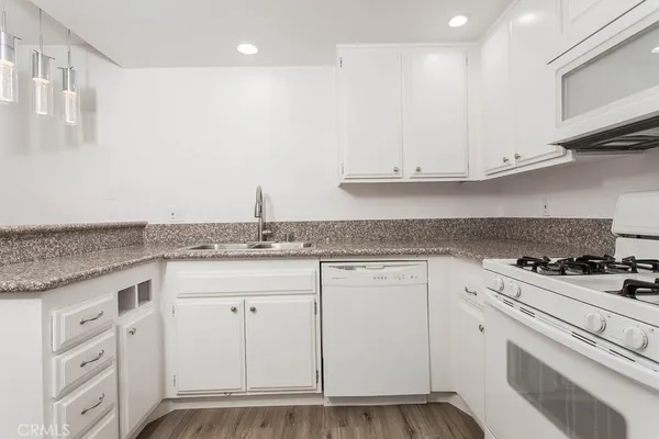 a kitchen with granite countertop a sink stainless steel appliances and white cabinets