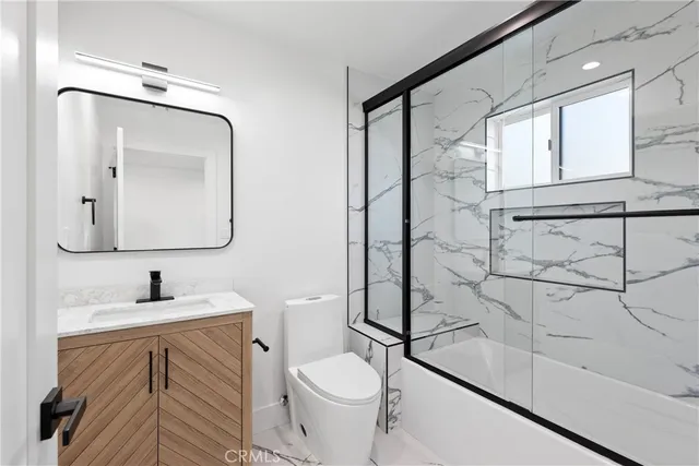 a bathroom with a granite countertop sink mirror vanity and toilet