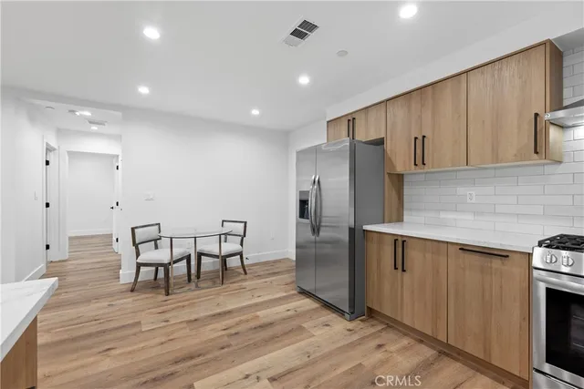 a kitchen with stainless steel appliances wooden floor and chair