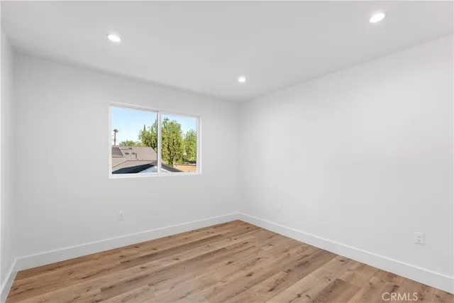 a view of an empty room with wooden floor and window