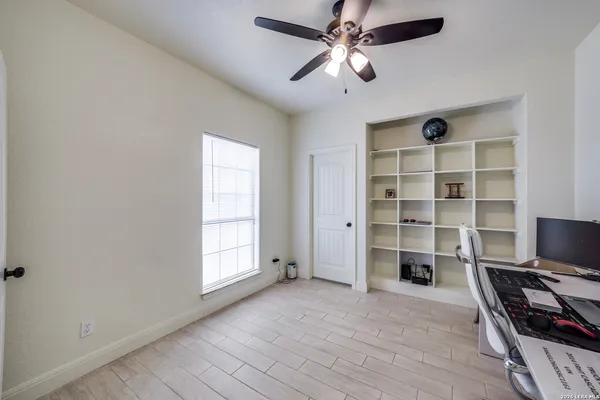 wooden floor in an empty room with a window and a kitchen