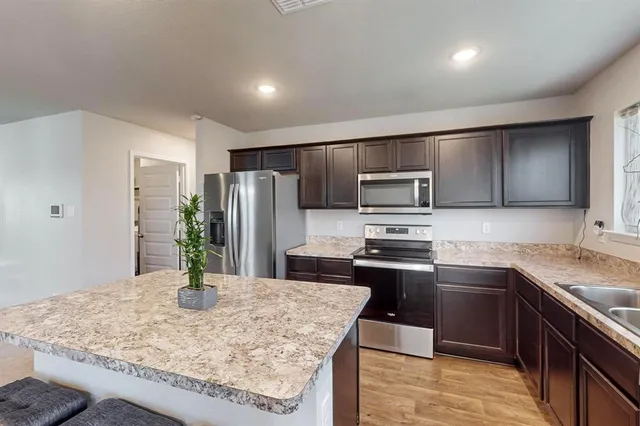 a kitchen with stainless steel appliances kitchen island granite countertop a sink dishwasher stove and refrigerator