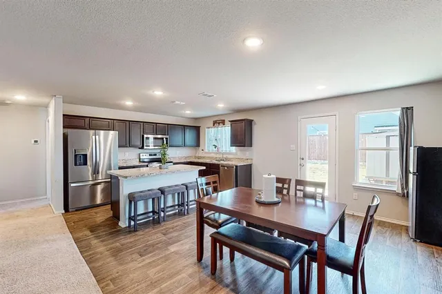 a living room with stainless steel appliances kitchen island granite countertop furniture and wooden floor