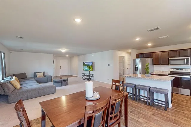 a living room with stainless steel appliances furniture and wooden floor