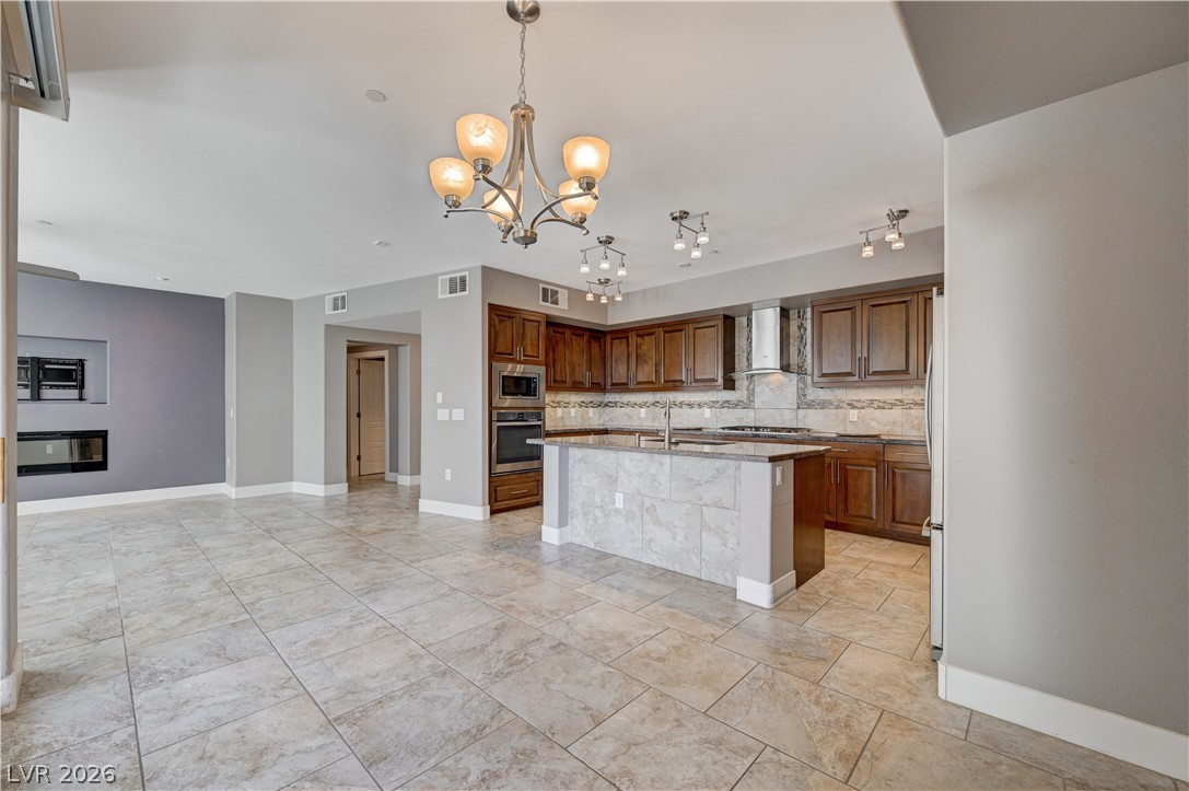 2555 Hampton Road, Unit 6108 Henderson, NV 89052 - Photo 12 of 63 Kitchen with tasteful backsplash, a chandelier, an island with sink, and wood finish cabinetry