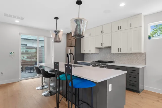 a kitchen with stainless steel appliances a stove a table chairs refrigerator and microwave