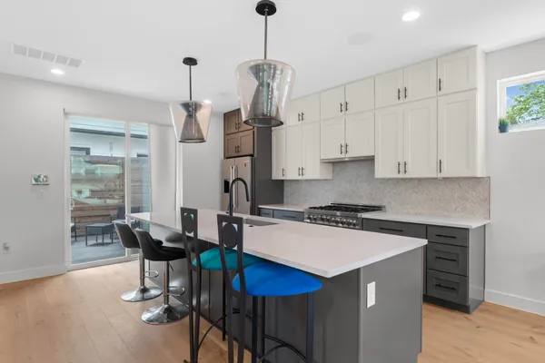a kitchen with stainless steel appliances a stove a table chairs refrigerator and microwave
