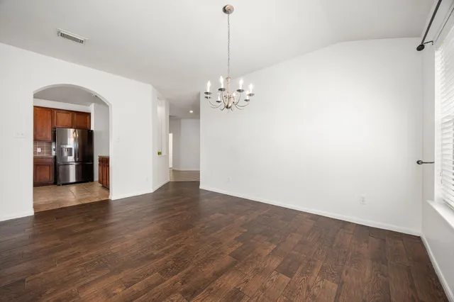 an empty room with wooden floor ceiling fan and windows