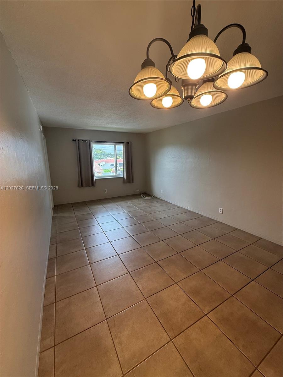 6841 Pembroke Road, Unit 15 Pembroke Pines, FL 33023 - Photo 3 of 16 a view of an empty room with a chandelier fan and kitchen view