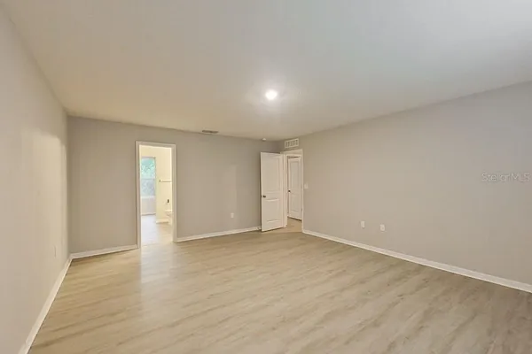 a view of an empty room with wooden floor and closet