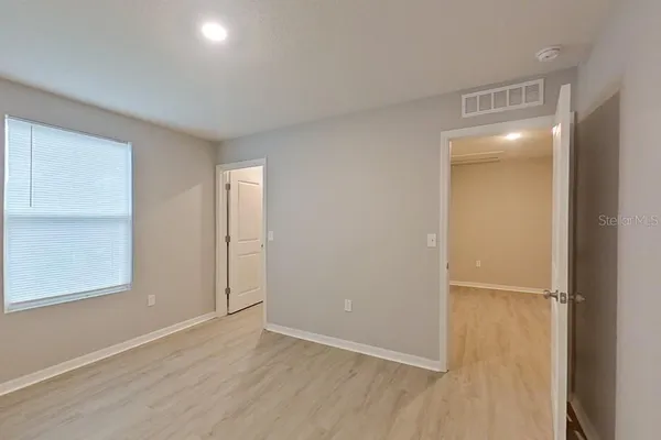 a view of an empty room with closet and a window