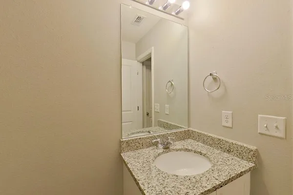 a bathroom with a granite countertop sink and a mirror