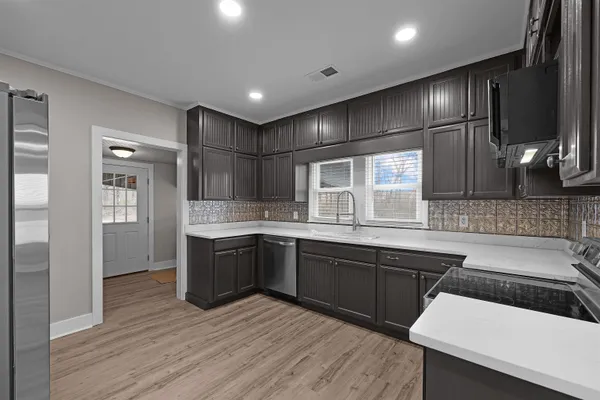 a large kitchen with granite countertop a sink and dishwasher a stove with wooden floor