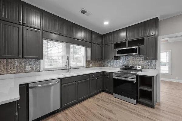 a kitchen with stainless steel appliances kitchen island granite countertop a sink stove and cabinets