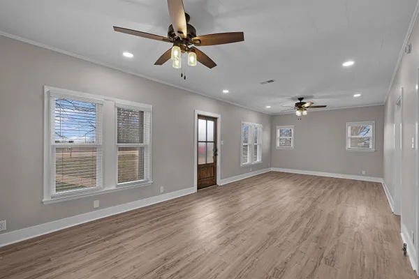 a view of an empty room with a window and wooden floor