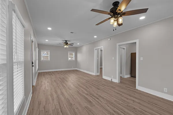 a view of an empty room with a window and wooden floor