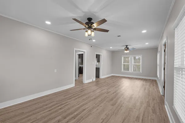 a view of an empty room with window and wooden floor